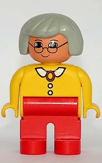 Duplo-Figur, weiblich, rote Beine, gelbe Bluse mit weißem Kragen und 2 Knöpfen, graues Haar, Brille